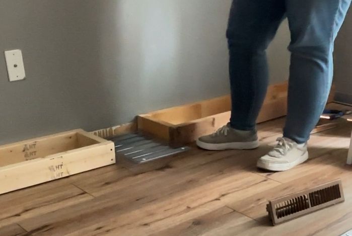 two 2x4 frames sitting on either side of a plastic floor vent extender